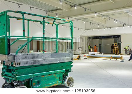 Scissor lift platform is inside of new big hall in building process.