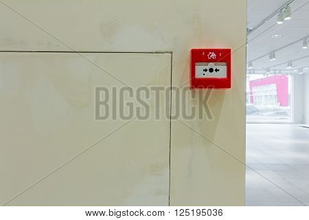 Red fire alarm panel box is on the wall to smash glass and press button. Every building is required to have a fire alarm.