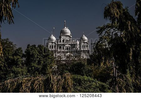 A shot of a meajestic white castle slightly hidden by trees around it. The shot was taken in Ajmer India.