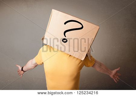 Young man standing and gesturing with a cardboard box on his head with question mark