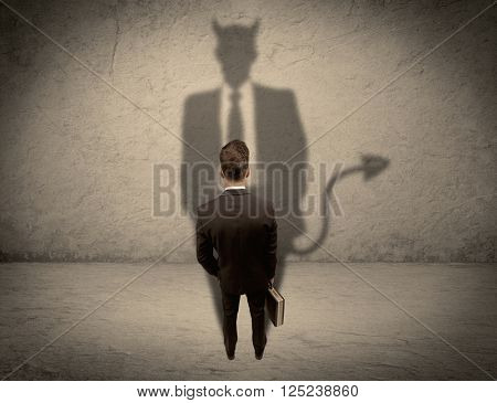 An experienced tricky businessman in suit looking at his devil desguise shadow reflected on the wall concept