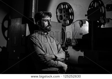beautiful hipster man standing near a film projector in the room projectionist