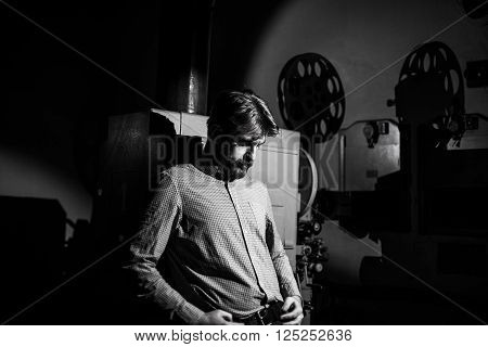 man standing near a film projector in the room projectionist