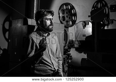 beautiful hipster man standing near a film projector in the room projectionist