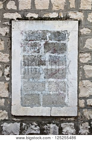 Ancient wall with walled up window by concrete brick