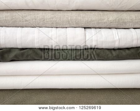 Stack of cool summer white and khaki clothes with different textures