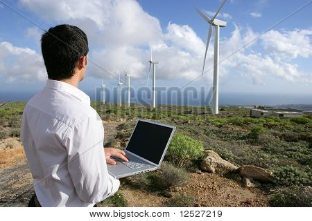 muž s přenosným počítačem před větrné turbíny