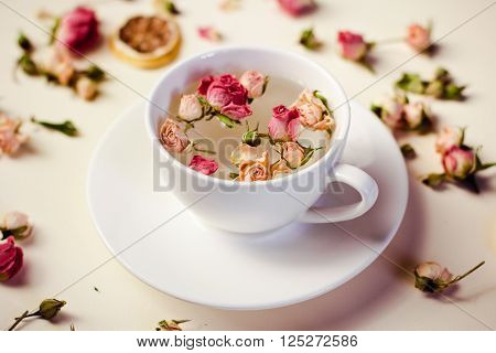 Herbal Tea In White Cup And Saucer With Roses And Dried Flowers Dried Round Slices Of Lemon Laid On