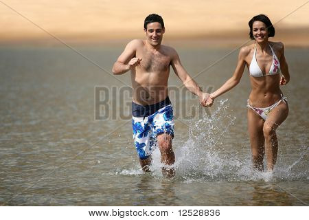 Man en vrouw lopen in het water hand in de hand