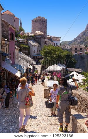 MOSTAR, BOSNIA AND HERZEGOVINA-JULY 20 2014: People walking through the Old Town with many shops and cafes on July 20, 2014 in Mostar, Bosnia and Herzegovina. Mostar is situated on the Neretva River.