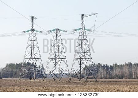 electricity transmission pylon silhouetted against blue sky. In the woods, at sunset.