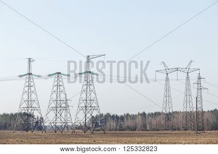 electricity transmission pylon silhouetted against blue sky. In the woods, at sunset.