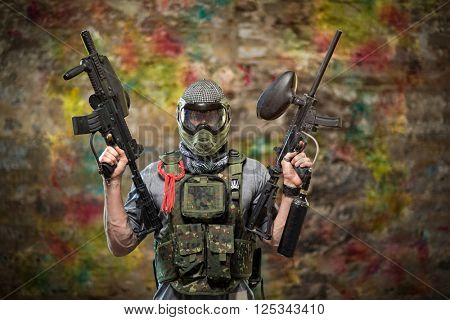 Handsome paintball gamer with guns in camouflage uniform 