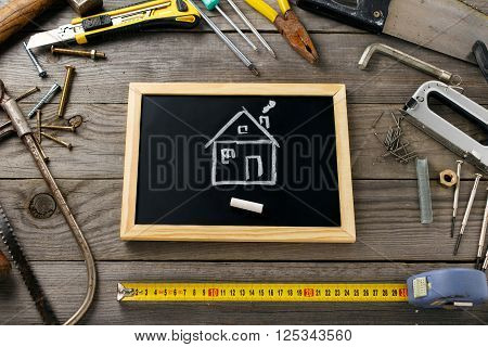 Picture chalk house with old tools on a wooden table in the workshop. Repair of houses concept