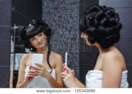 Cute girl doing selfie in the bathroom. Morning makeup. The reflection in the mirror. Self-portrait.