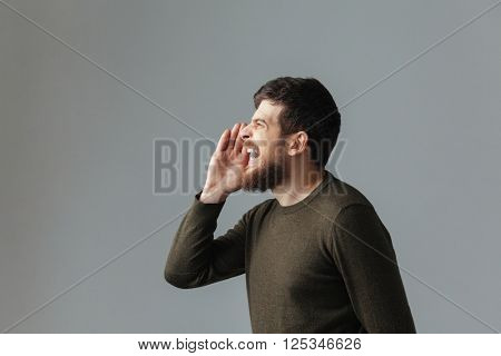Side view portrait of a man shouting over gray background