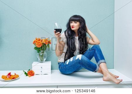 Young attractive woman drinking red wine at home. Relax after work. Girl barefoot and with her long hair.