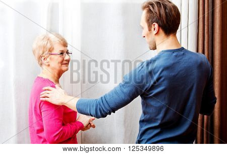 Mother and son standing next to the window and talking to each other 