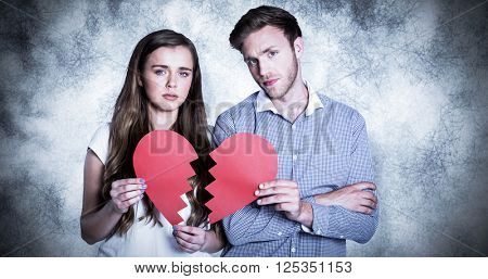 Couple holding broken heart against grey background