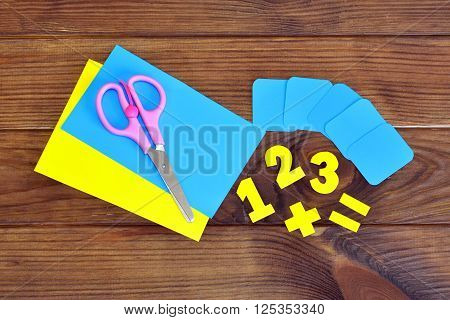 Paper sheets and numbers, scissors on a brown wooden background
