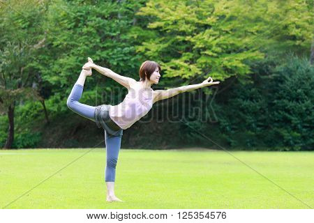 Japanese woman outside doing yog Lord of the Dance Pose