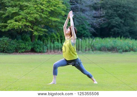 Japanese woman outside doing yoga warrior I pose