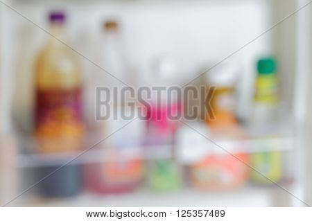 Blurred pictures of ketchup, salad dressings, mayonnaise and sauces bottles arranged side by side inside a refrigerator.