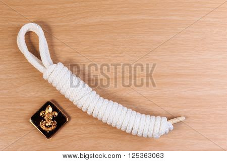 Orderliness White Scout Rope With Vintage Boy Scouts Badge On Wooden Table.