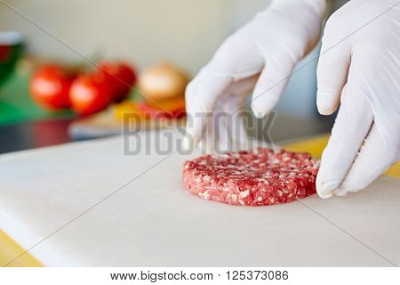Cropped image of hands wearing white latex gloves preparing a hamburger patty in a clean and hygeinic environment
** Note: Shallow depth of field