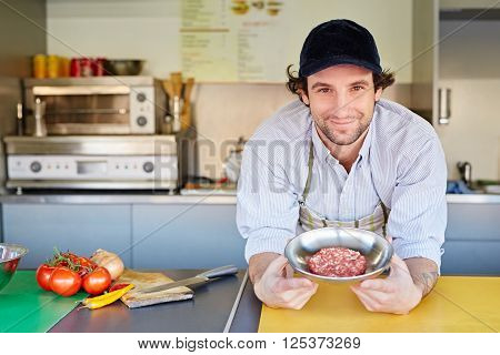 Takeaway food entrepeneur standing proudly next to a bowl of fresh high-quality minced red meat with which he makes his hamburger patties