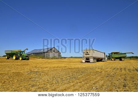 MAYVILLE, NORTH DAKOTA-August 19, 2015: A harvest scene of a tractor and grain cart cart,  products of John Deere Co, an American corporation that manufactures agricultural, construction, forestry machinery, and diesel engines.