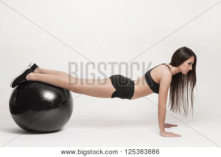 Portrait of young attractive woman doing exercises. Brunette with fit body exercising with fitness ball. Series of exercise poses.