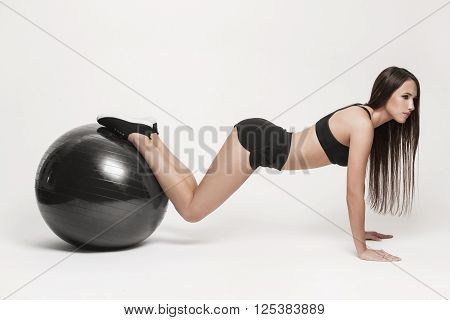 Portrait of young attractive woman doing exercises. Brunette with fit body exercising with fitness ball. Series of exercise poses.
