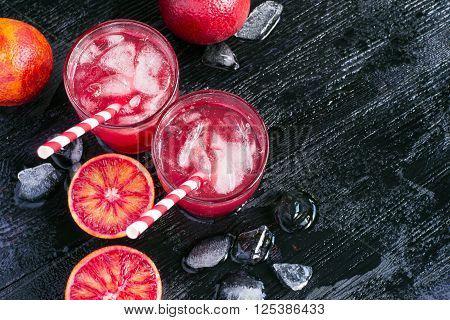 Juice of blood orange fruit halves and ice top view space for text