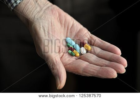 Old age pensioner holding daily drug medications.