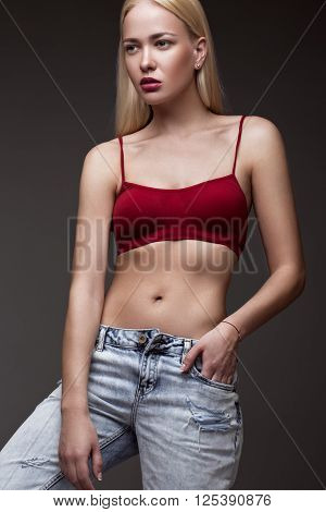 sexy fashion model with long hair, young European attractive, beautiful eyes, full lips, perfect skin is posing in studio for glamour vogue test photo shoot showing different poses. Picture taken in the studio on a gray background.