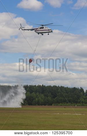 Minsk Belarus-June 21 2014: Staff of Ministry of Emergency Situations Spraying Water over Trees on MI-8 Helicopter During Aviation Sport Event Dedicated to the 80th Anniversary of DOSAAF Foundation in Minsk on June 21 2014 in Minsk Belarus