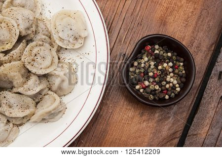 Meat dumplings - russian pelmeni on wooden background. 