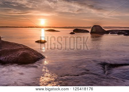 Colorful sunrise over the sea viewed from the beach rocks