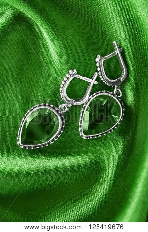 Vintage emerald earrings on green satin as a background