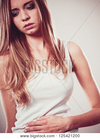 Bellyache indigestion or menstruation. Young woman suffering from stomach pain studio shot on gray