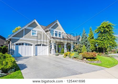 Custom built luxury house with nicely trimmed and designed front yard, lawn in a residential neighbourhood in Canada.
