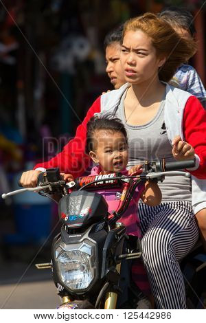 THONG PHA PHUM, THAILAND, JANUARY 23, 2016 : Three adults and a child are riding a scooter without helmet protection in the street of Thong Pha Phum, Thailand.