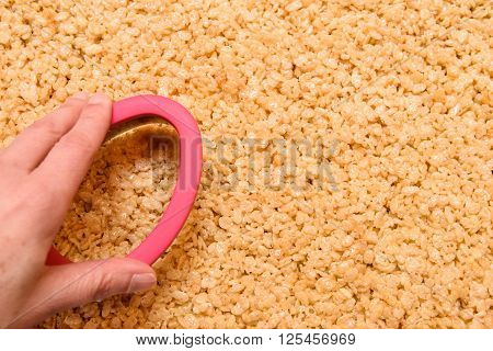 Hand with Easter cookie cutter and sheet of crispy rice and marshmallow treats