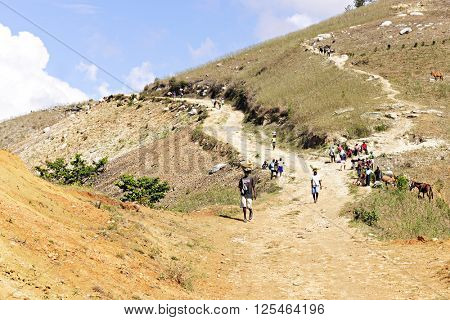 FOND BAPTISTE, HAITI - FEBUARY 18, 2016 - A wide view multiple people walking towards a weekly market (market not in view).