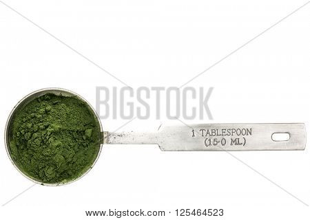Nutrient-rich organic spirulina  powder - isolated measuring metal tablespoon, top view