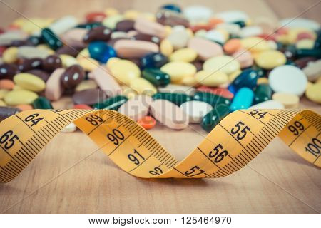 Vintage photo Tape measure and colorful medical pills capsules or supplements for therapy or weight loss concept of treatment health care and slimming