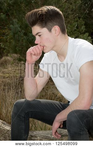 Thinking teenage boy sitting in a prak