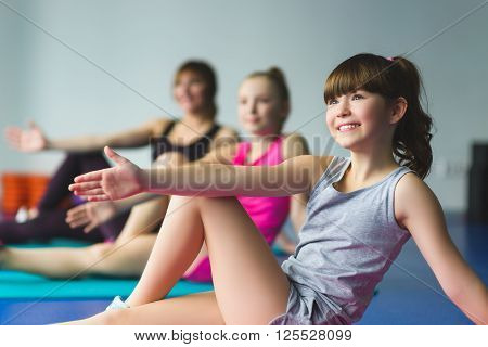 Girls and Instructor or mother doing gymnastic exercises  in fitness class.