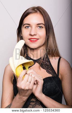 Young amazed woman in lacy lingerie holding a banana, she is going to eat a banana.
